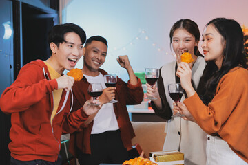 Group of young Asian man and women as friends having fun at a New Year's celebration, holding gift boxes standing by Christmas tree decoration, midnight countdown Party at home with holiday season.