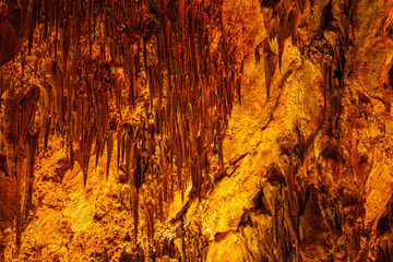 Brown stone mineral formations on the wall in Damlatas cave in Alanya Turkey, close-up. Natural abstract brown-orange background of stalactites and stalagmites