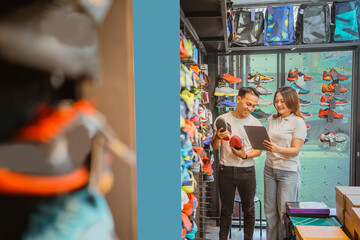 athletic footwear store employee holding tablet and shoes