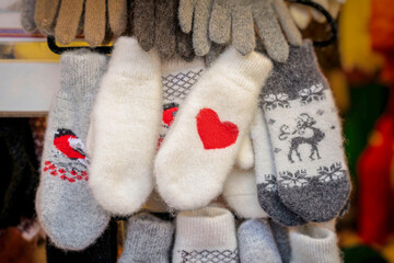 Display of colorful winter mittens featuring festive patterns and warm designs in a cozy market setting