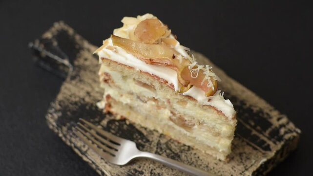 Layered sweet cake with cream, pear and dorblu cheese on a dark concrete background