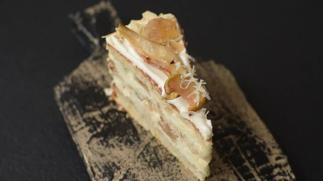 Layered sweet cake with cream, pear and dorblu cheese on a dark concrete background