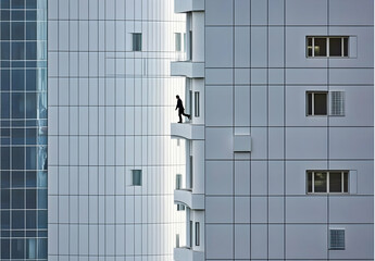 Obraz premium Minimalist Photograph of an Office Worker Walking Along the Edge of a Building in a Modern Urban Landscape with Clean Lines and Contemporary Architecture