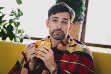 Young man enjoying a relaxed weekend morning indoors, sipping hot beverage in cozy autumn apartment