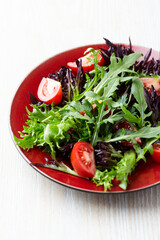 Salad with fresh tomatoes and arugula on a bright stone background. Close up. Copy space.	