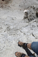 mountain boots of the hiker walking on the ledge of the path a short distance from the precipice