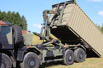 Military truck transporting war supplies while unloading container at the battlefield