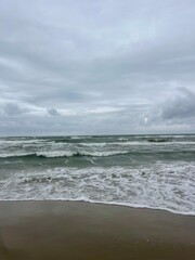 cloudy seascape, sandy shore, empty wild beach, clouds and waves