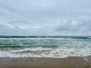 cloudy seascape, sandy shore, empty wild beach, clouds and waves