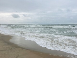 cloudy seascape, sandy shore, empty wild beach, clouds and waves