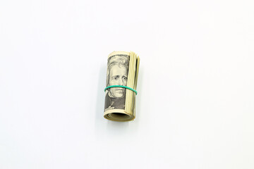 A bundle of American dollar bills surrounded by a green rubber band on a white background.