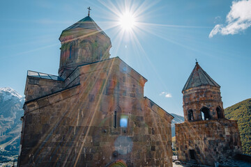 A beautifully preserved ancient stone church, the Gergeti Trinity Church in Kazbegi, Georgia, is captured under a vibrant blue sky. 