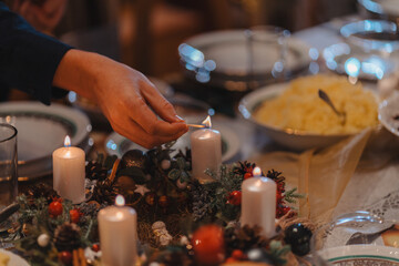 Christmas supper - lighting candles on a table that has been decorated and prepared for the meal. A warm, festive atmosphere. 