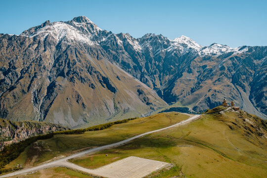 View on the Gergeti Trinity Church in Stepantsminda with the snow covered Caucasus mountains in the background, in Kazbegi, Georgia
