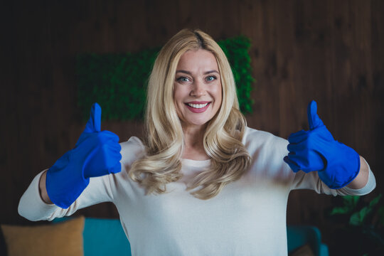 Photo of positive good mood woman dressed white shirt doing housework showing two thums up indoors house apartment room