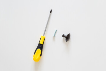 Manual screwdriver and dark black handle on light gray table background. Assembling new wooden furniture. Closeup. Top down view.