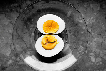 Yellow egg yolk on a glass plate on black and white background