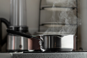 Boiling water with steam in a pot on an electric stove in the kitchen. 