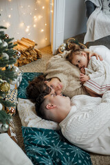 Family sitting near the Christmas tree and opening presents. Winter holidays.