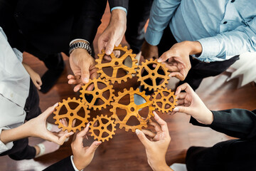 Group of multiracial business people joining gear wheels together as effective unity and productive teamwork concept. Efficient system business team process for solution solving. Meticulous