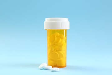 Bottle of antibiotic pills on light blue background