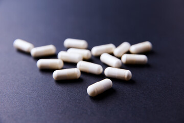 Creatine capsules on dark paper background. Soft focus. Copy space.	