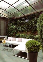 cozy veranda with white sofa, glass ceiling and lots of greenery
