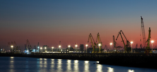 Landscape with sunset in the harbor. The silhouettes of the Constanta port cranes in the evening