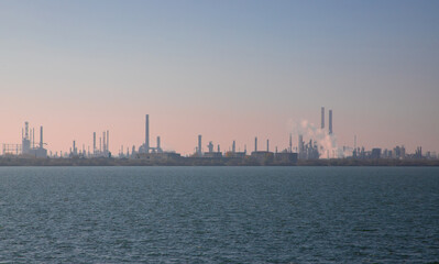 Fototapeta premium Landscape with the silhouette of a refinery seen from a distance