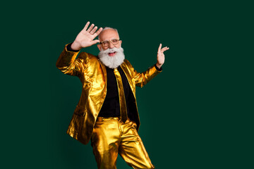 Charismatic elderly man in vibrant golden suit celebrating a holiday with cheerful pose against green background