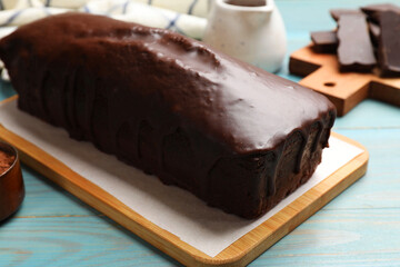Tasty chocolate sponge cake on light blue wooden table, closeup
