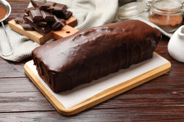 Tasty sponge cake and pieces of chocolate on wooden table, closeup