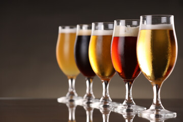 Glasses with different types of beer on mirror surface, closeup. Space for text