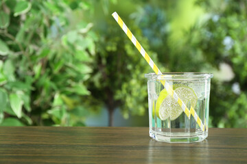 Glass of soda water with lime on wooden table against blurred background. Space for text