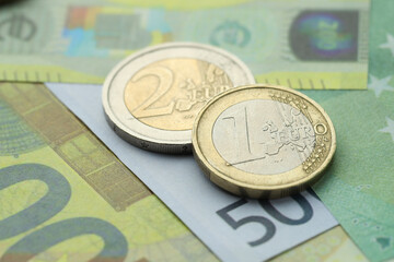 Different coins on euro banknotes, closeup view