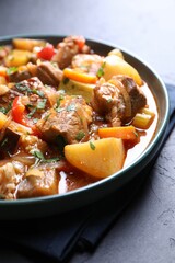 Delicious stew with vegetables on black table, closeup