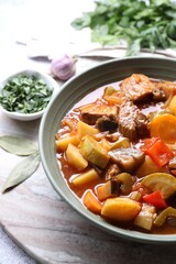 Delicious stew with vegetables in bowl and spices on table, closeup