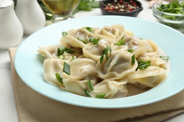 Delicious pelmeni with green onion served on white table, closeup