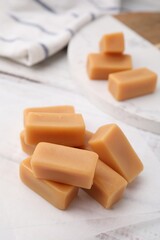 Tasty sweet caramel candies on white table, closeup