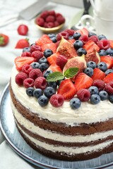Delicious chocolate sponge cake with berries on white table, closeup