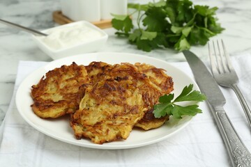 Delicious potato pancakes served on white marble table, closeup