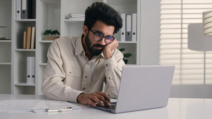 Tired bored Arabian Indian man businessman lazy employee manager boring job working with laptop...