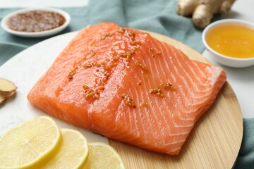 Salmon fillet with mustard and lemon slices on table, closeup