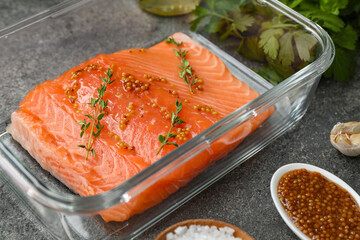 Salmon fillet with spices in dish on gray textured table, closeup