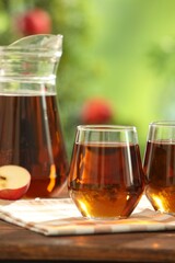 Tasty freshly made apple juice in glasses on table outdoors