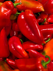 A vibrant close-up of fresh red bell peppers, showcasing their glossy surface, rich color, and natural texture. Perfectly stacked, they highlight freshness and culinary appeal.