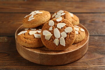 Tasty cookies with almond flakes on wooden table, closeup
