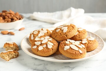 Tasty cookies with almond flakes and nuts on white marble table, closeup