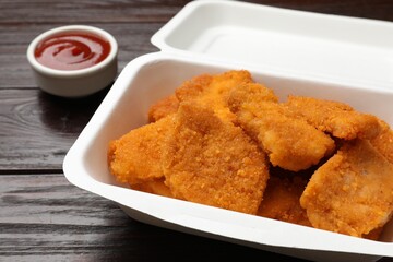 Tasty chicken nuggets and sauce on wooden table, closeup