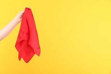 Woman holding red handkerchief on yellow background, closeup. Space for text